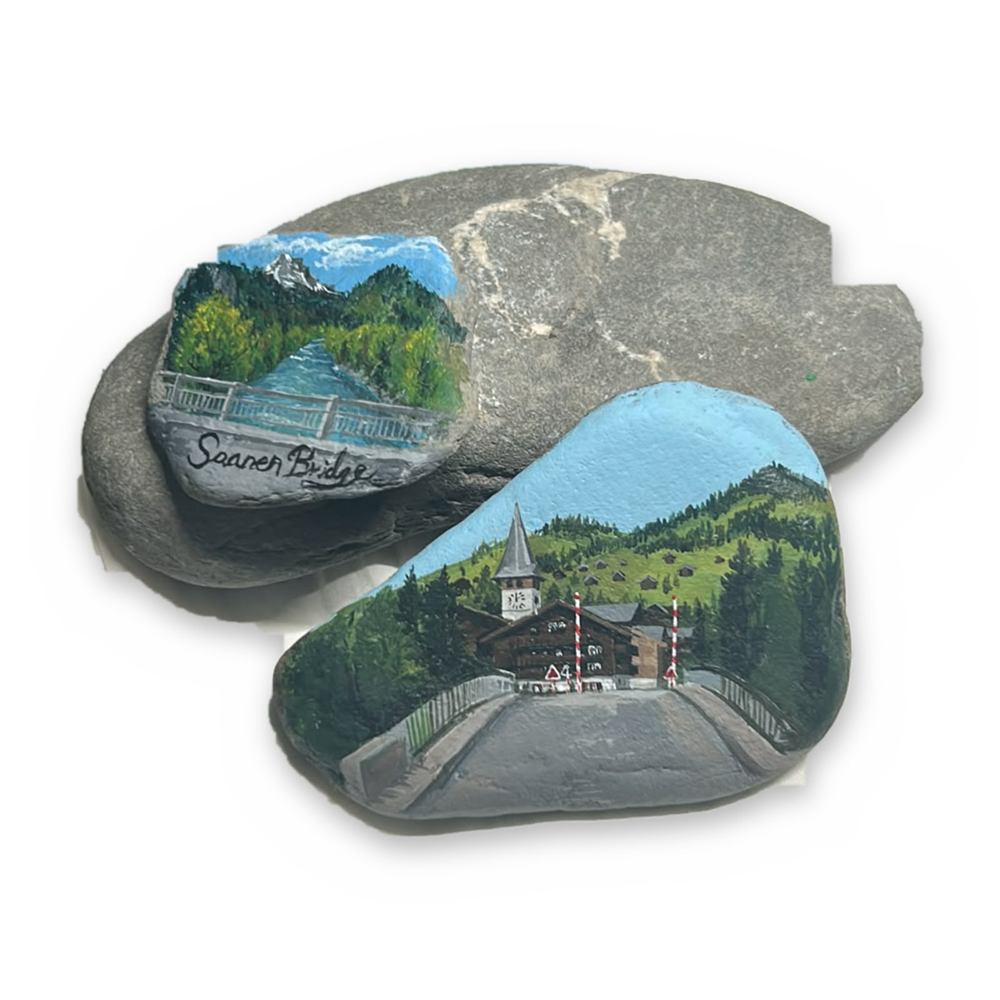 Two river stones painted with Saanen bridge scenes